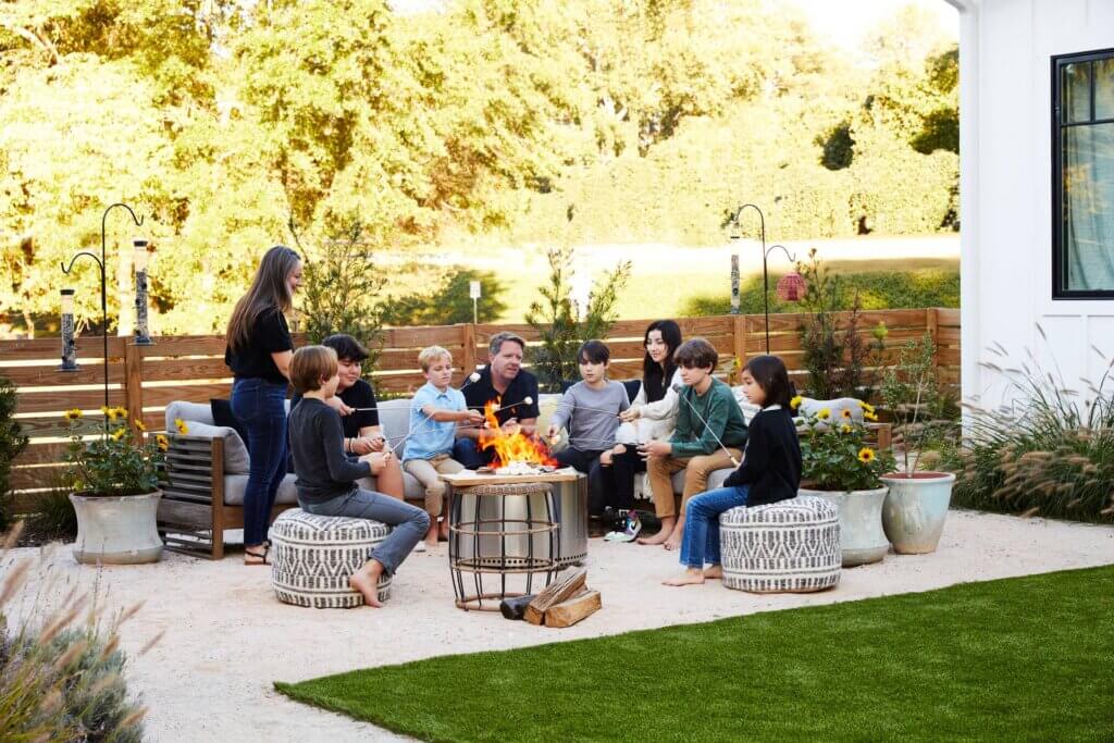 Large family roasting smores around a stainless steel firepit