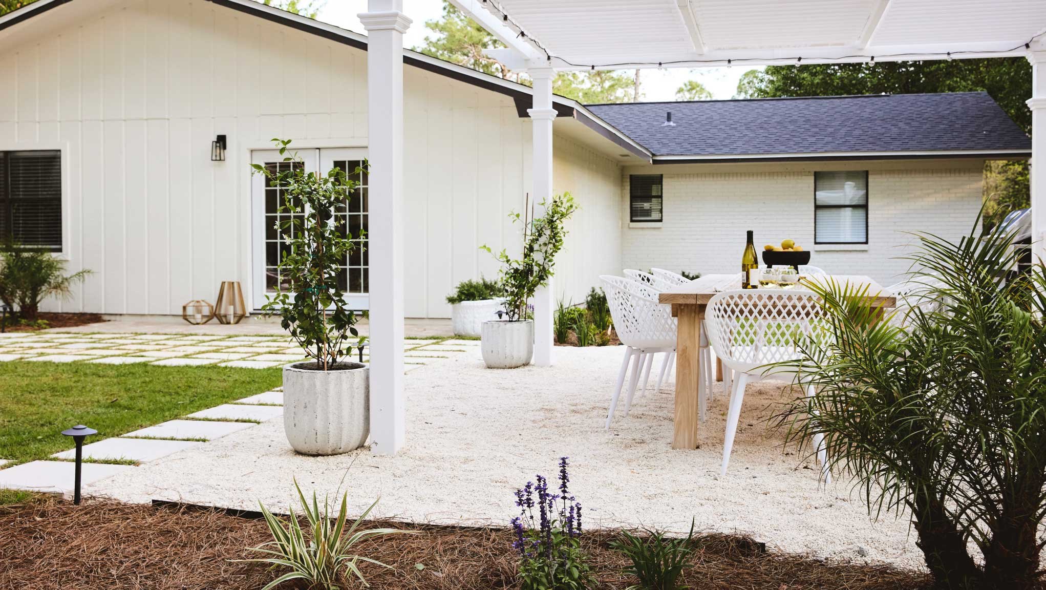 Backyard with gravel patio and dining set with planting bed in foreground