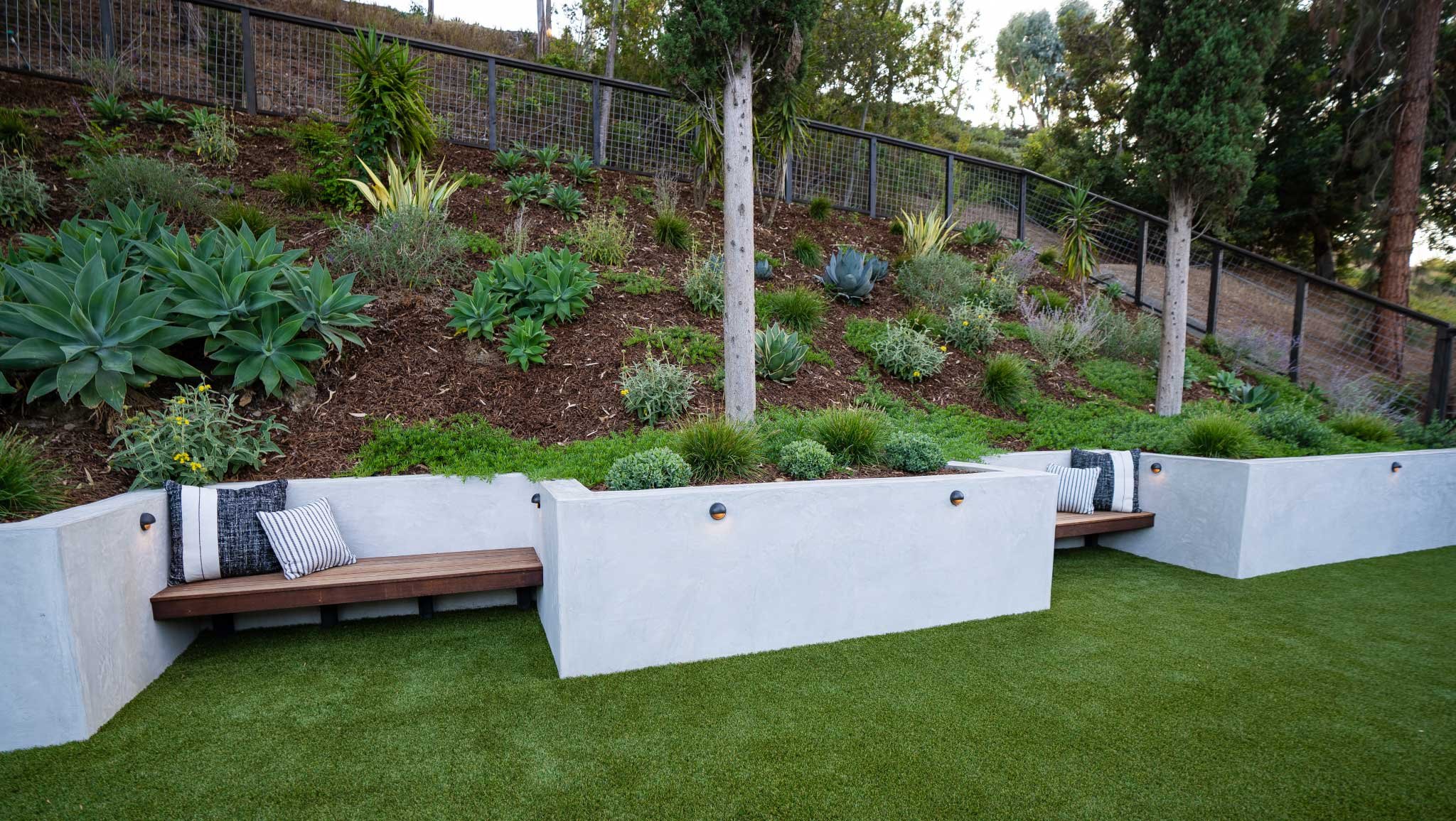 Close up of retaining wall with built in benches and plantings on slope