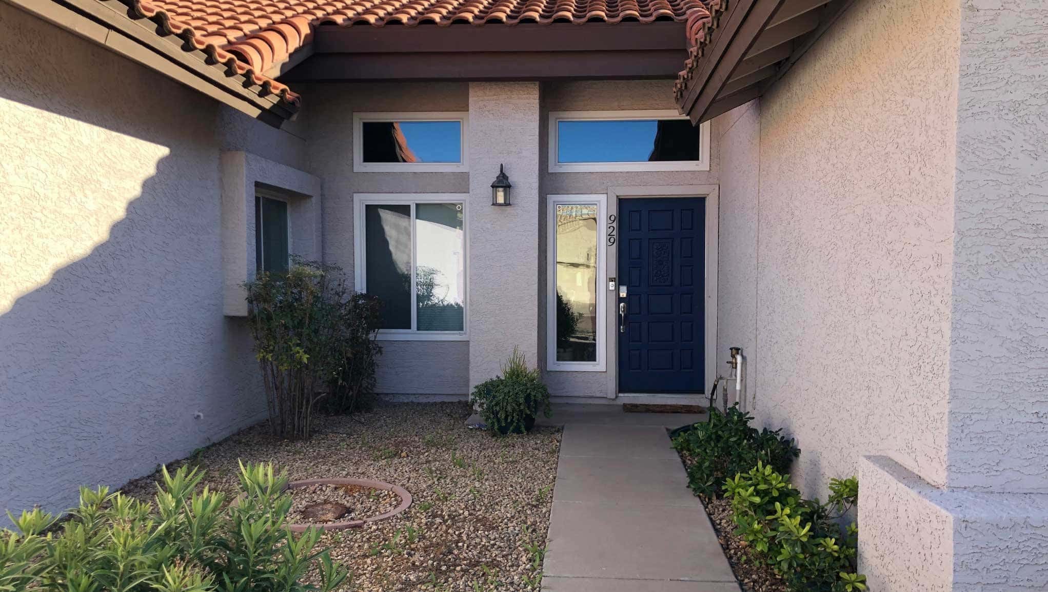 Before photo of home entryway with dated concrete walkway and struggling plants