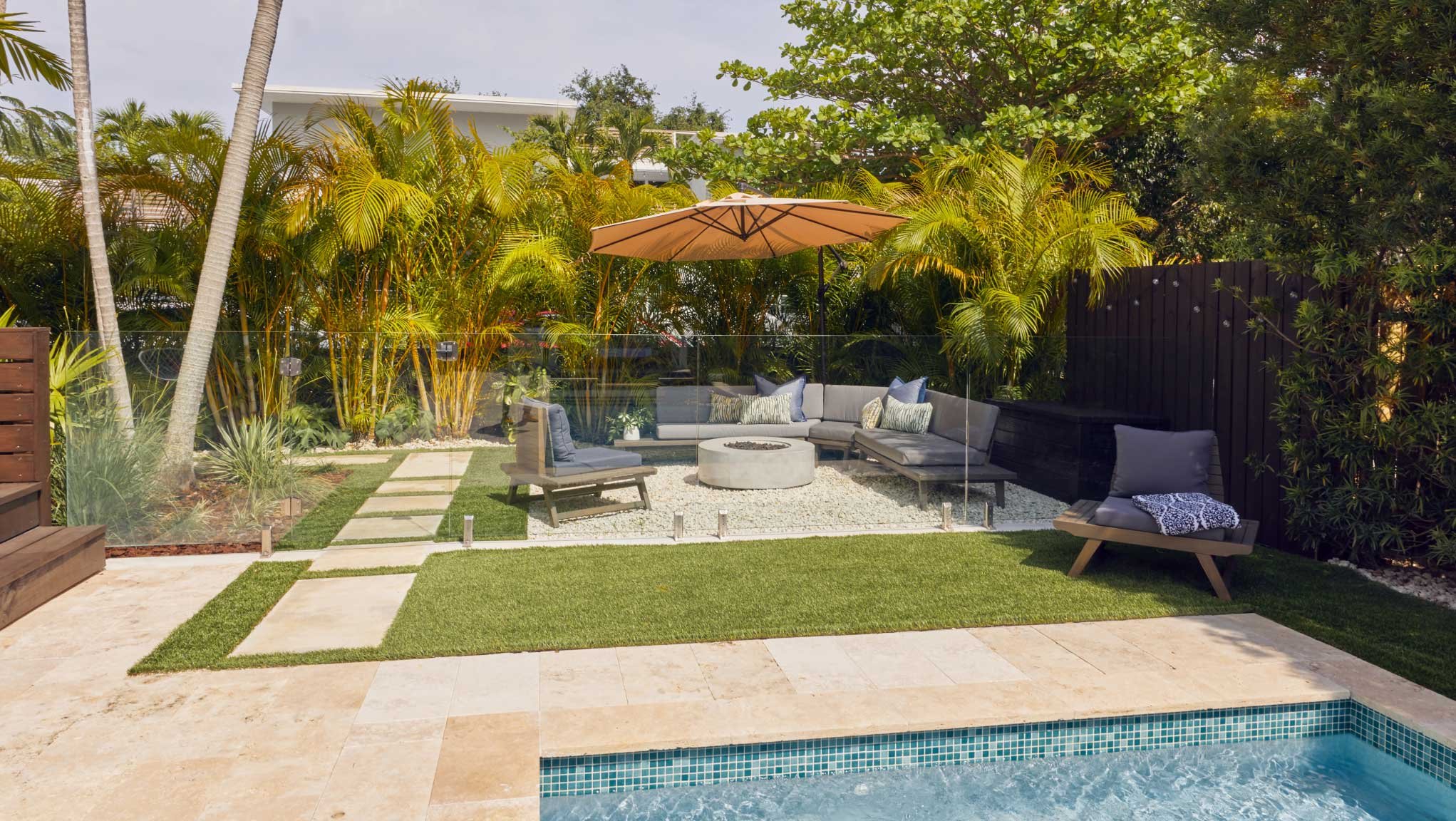 Stylish backyard with pool, stepper path, and plexiglass wall containing an outdoor lounge area
