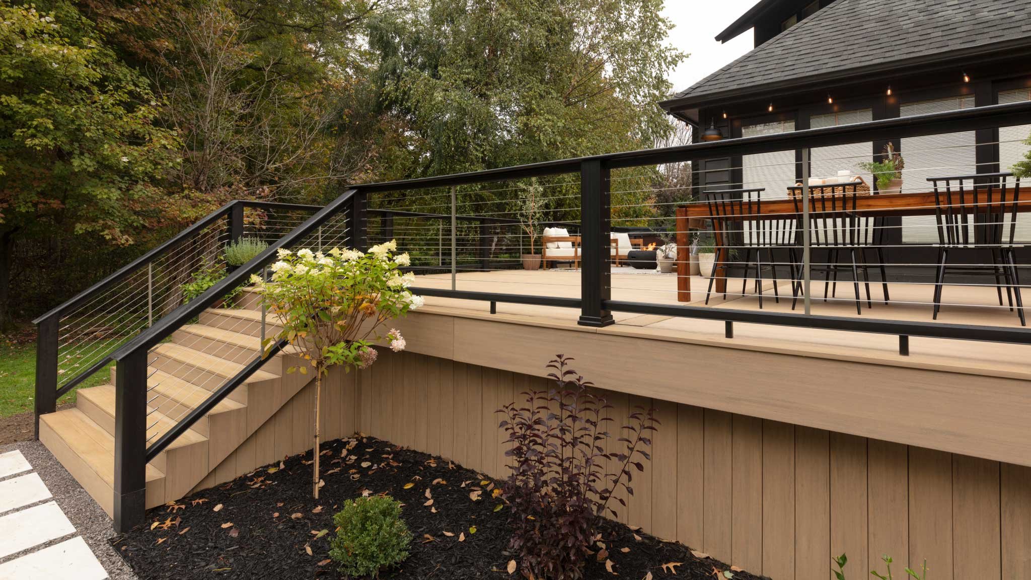 Finished deck with black metal railing and planting beds bordering