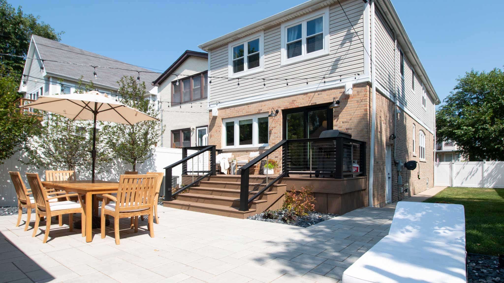 Clean backyard with outdoor dining set and modern deck with black railing