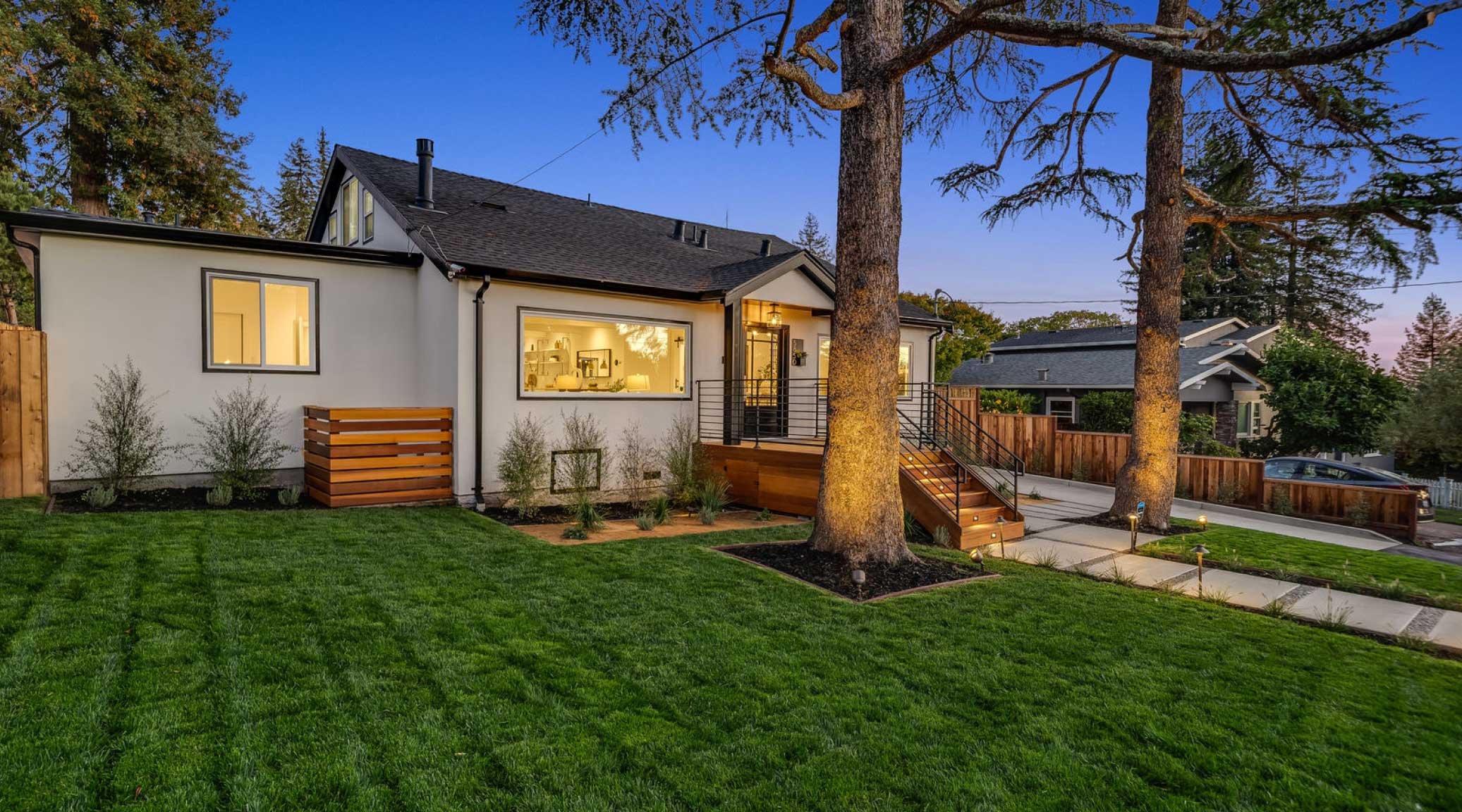 Side view of finished front yard with green lawn, large tree, and planting beds