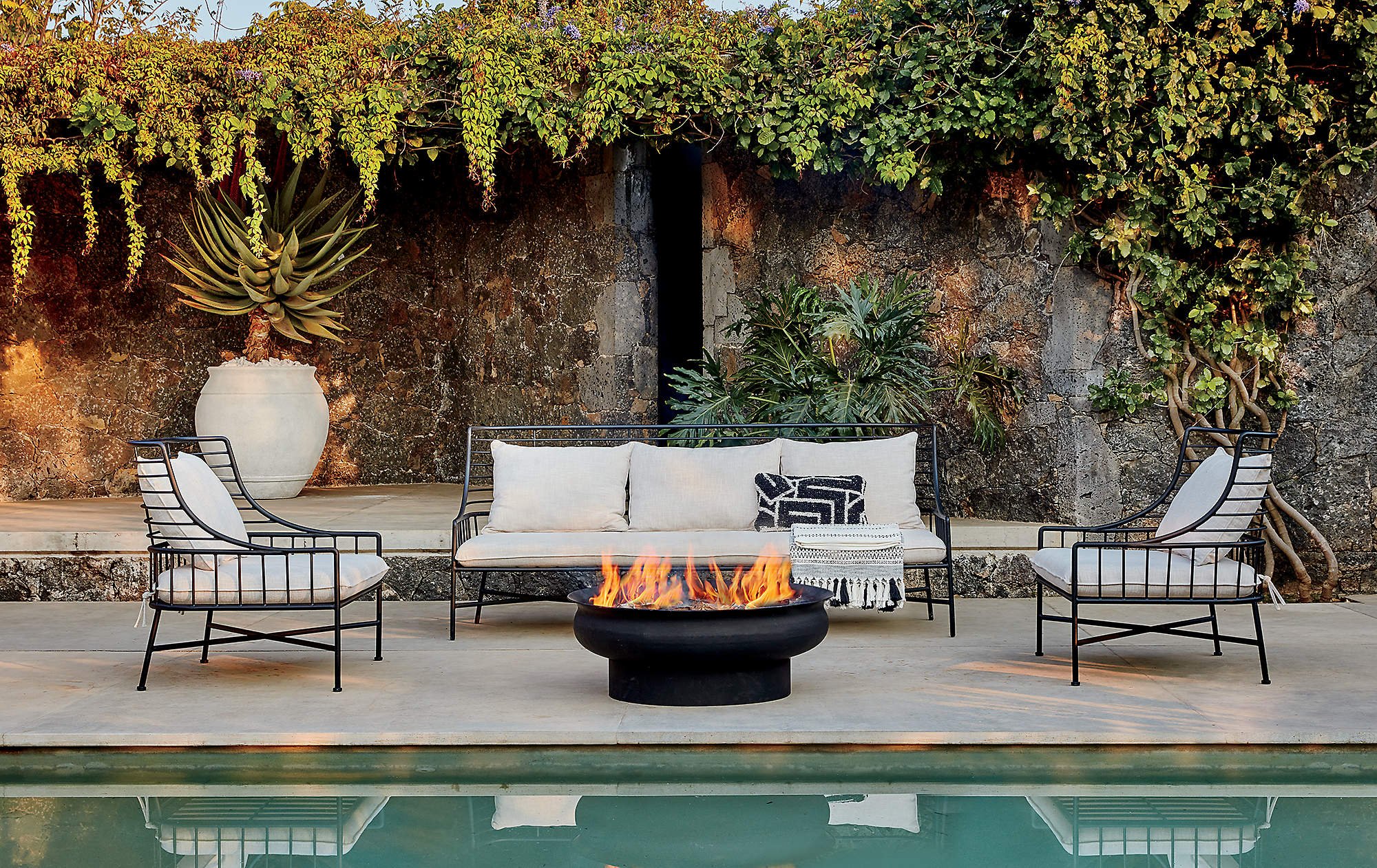 A fenced yard with a sitting area and a fire pit and a plunge pool