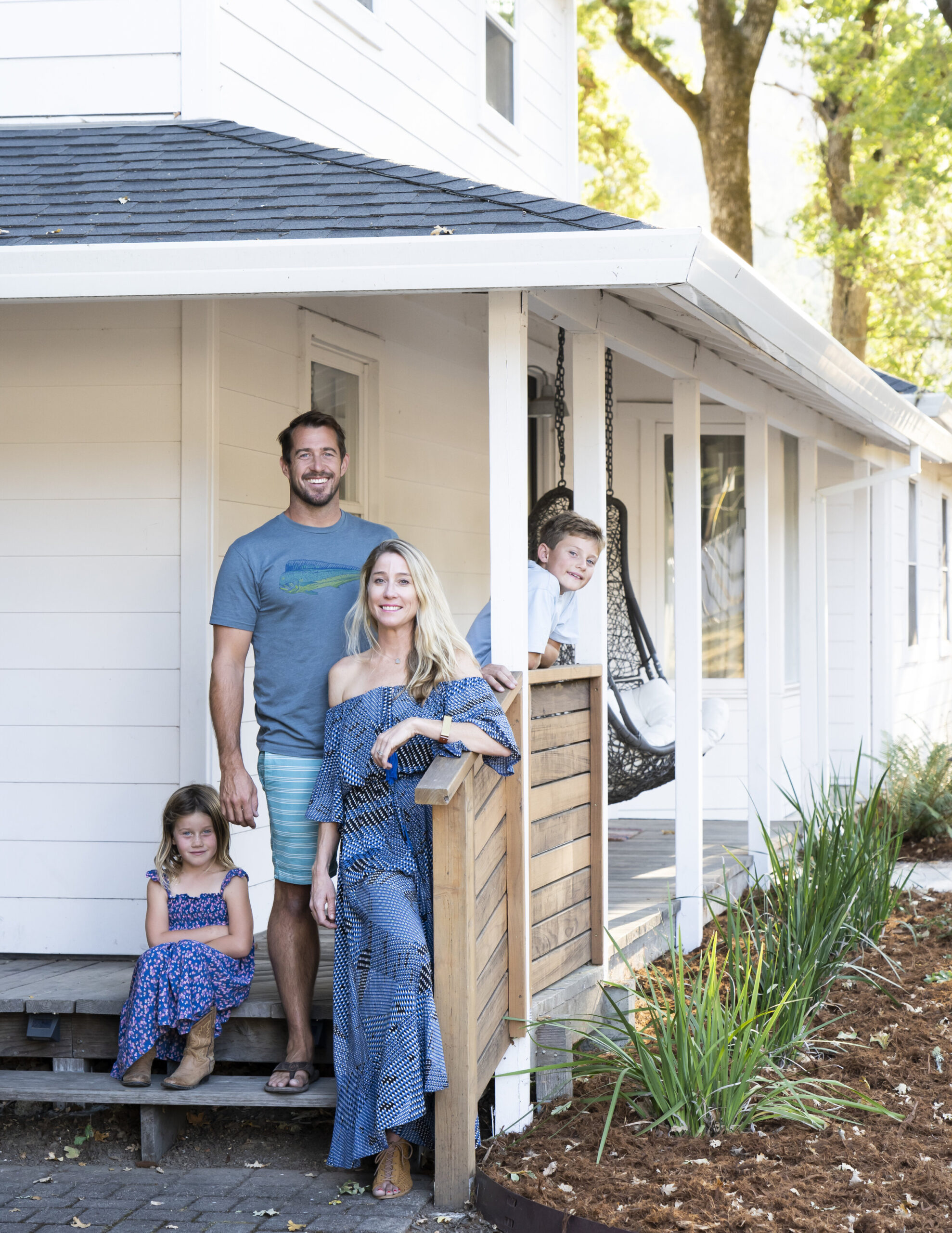A family of four standing on their porch with low water plants next to them