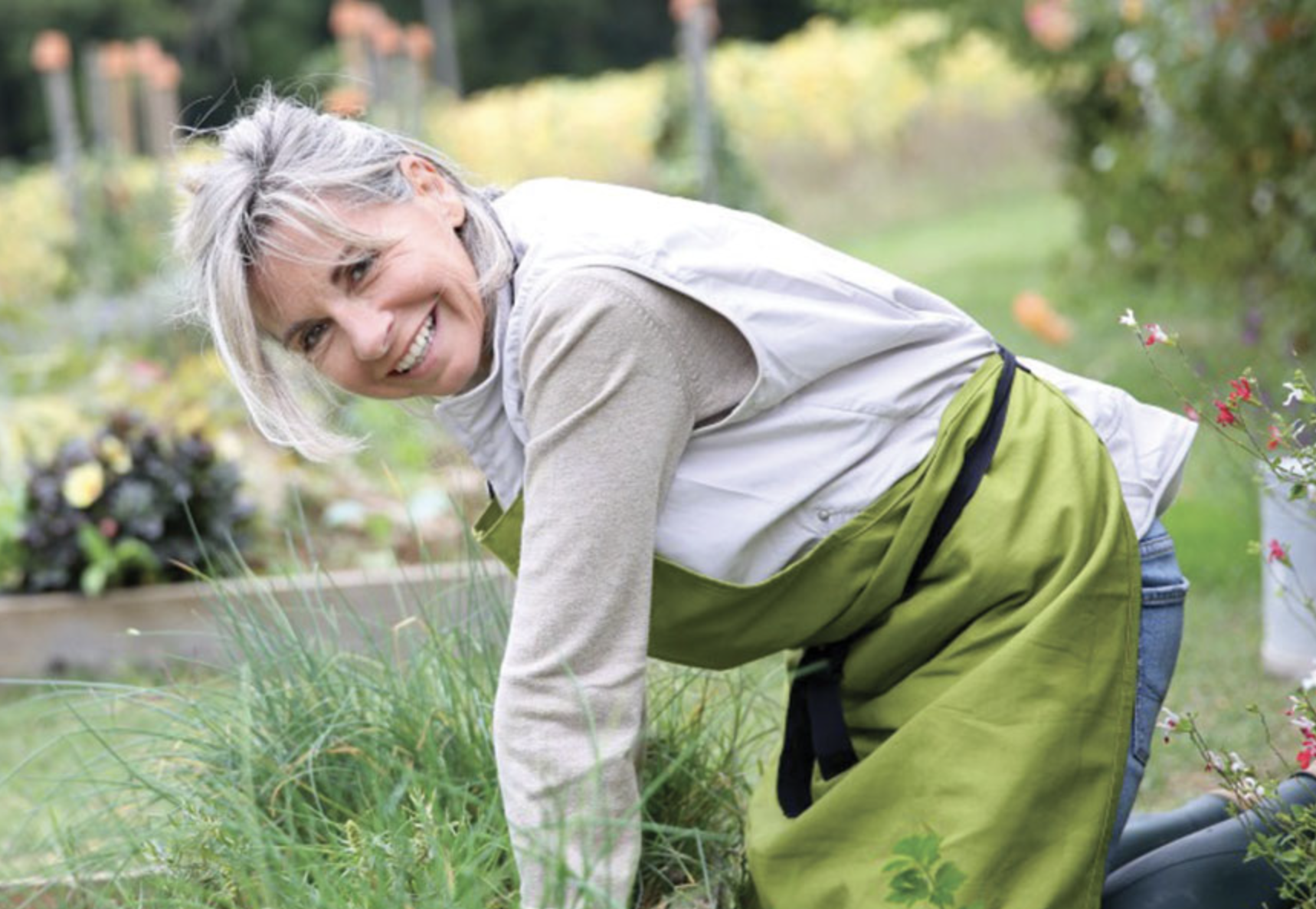 Lady wearing a green apron while maintaining a garden.