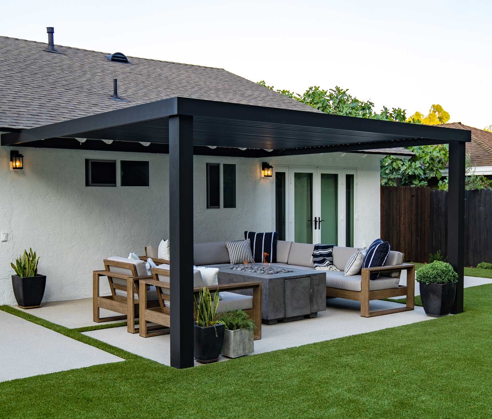 Pergola over an outdoor sitting area with fire pit and lawn surrounding it.