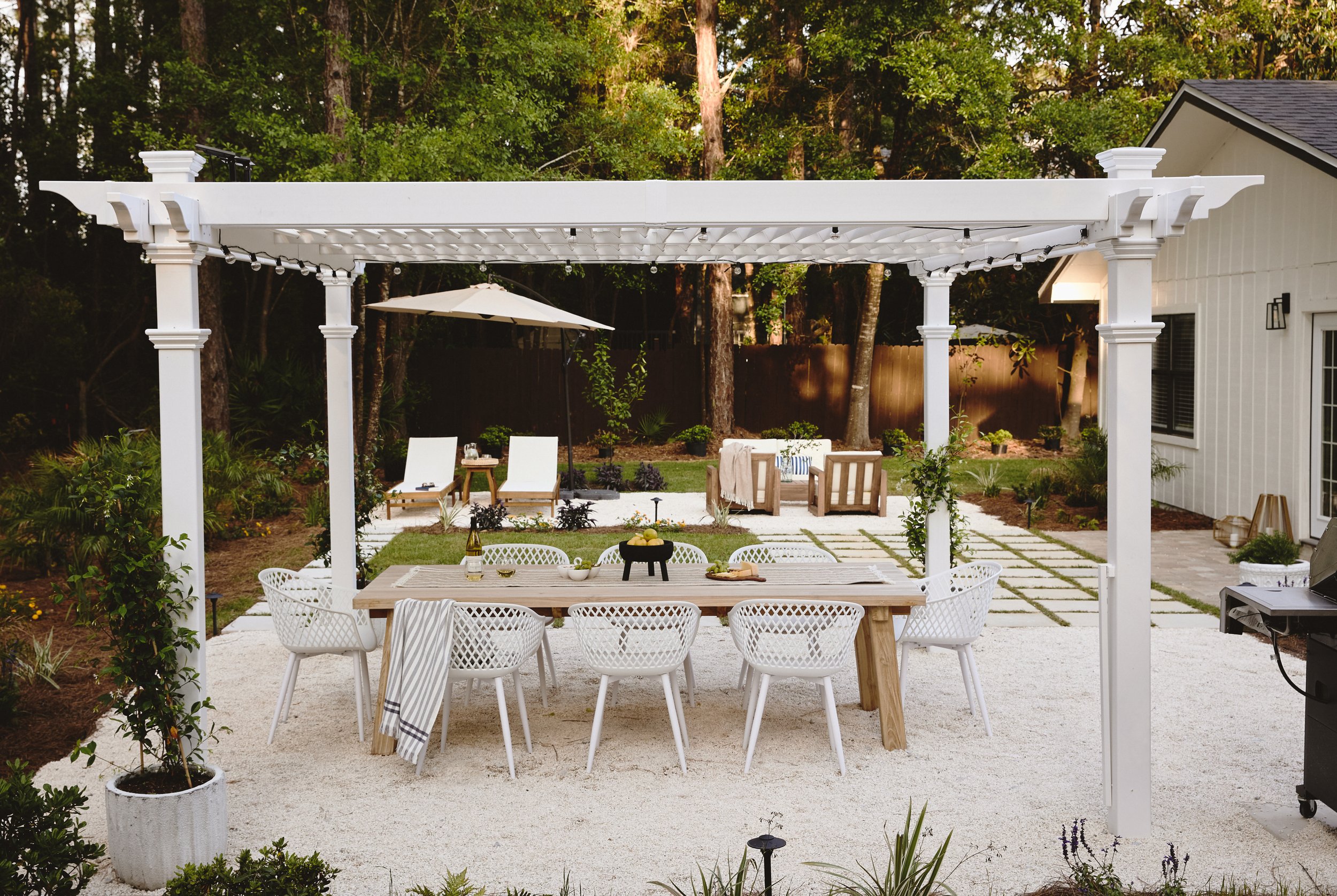 Traditional white vinyl prefab pergola in a lush backyard