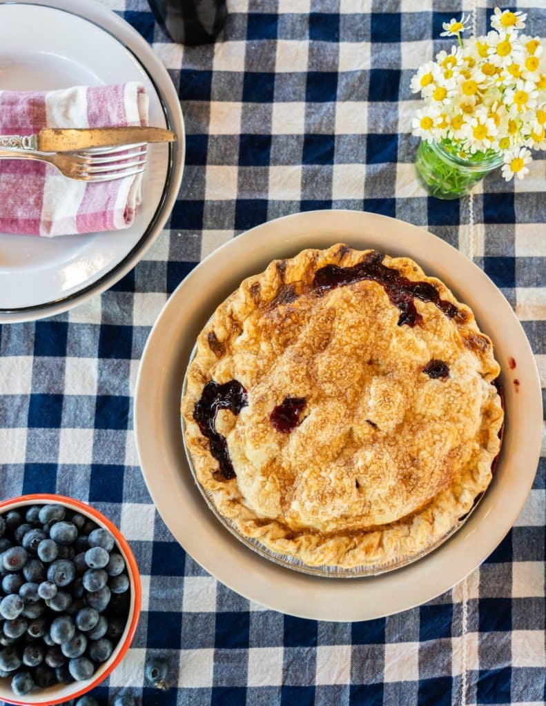 A bowl of pie and some blue berries on a dining table 
