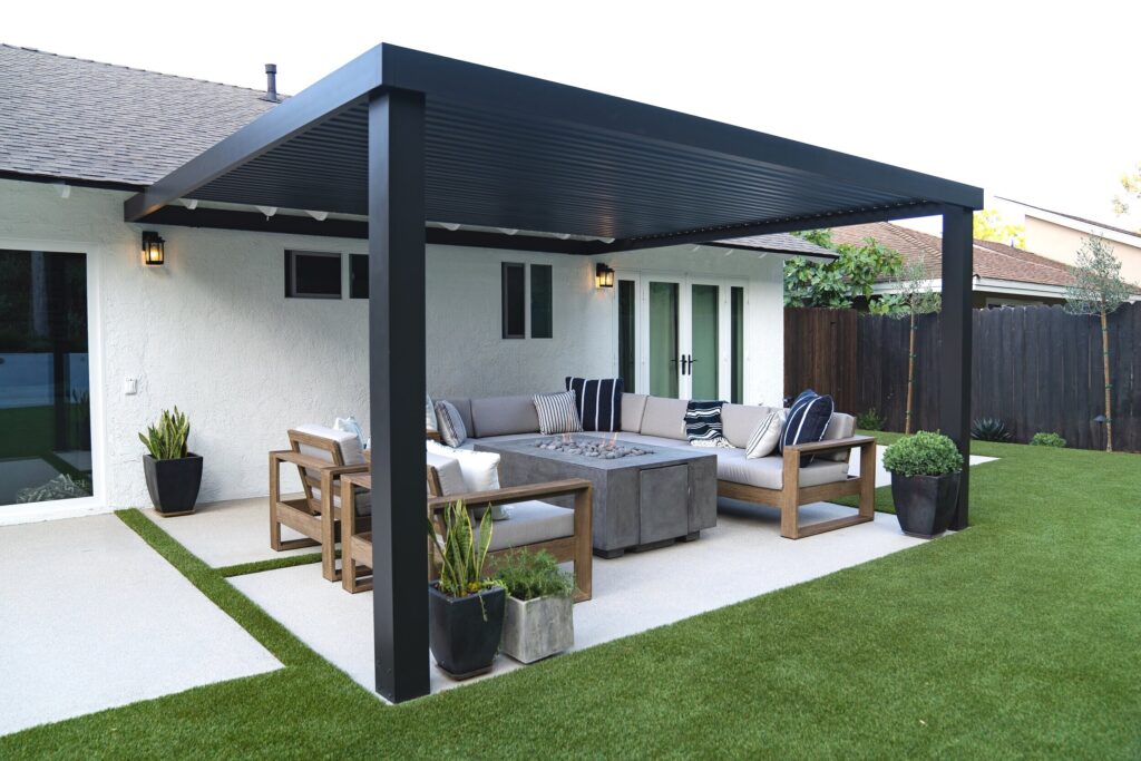 Modern black pergola covers outdoor fire pit lounge area in a Yardzen-designed back yard