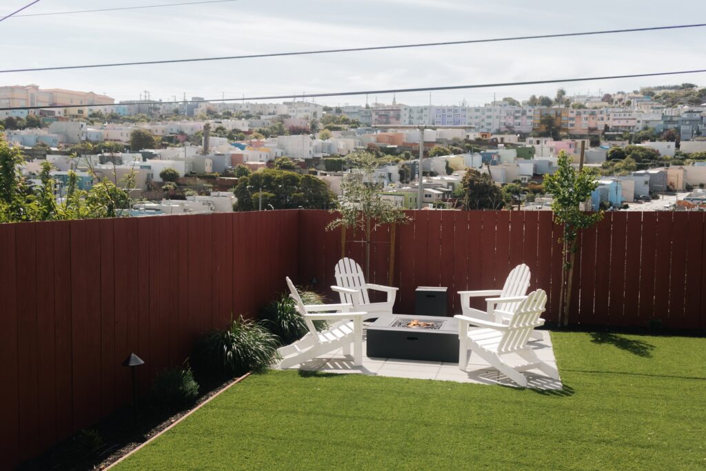 Fire pit area with white Adirondack chairs in San Francisco back yard