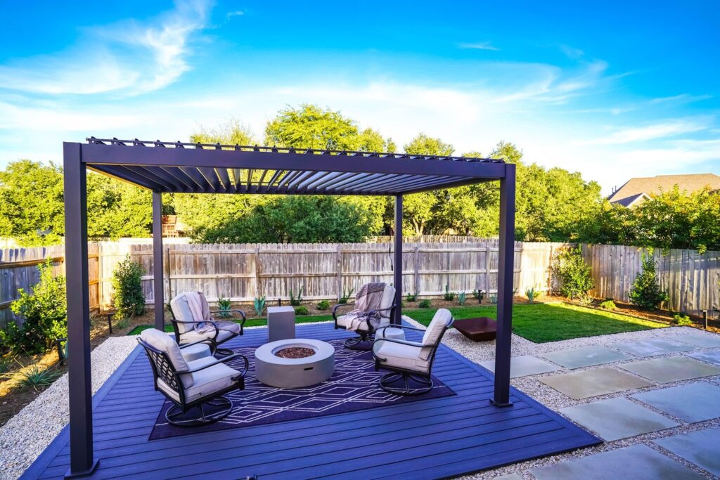 Backyard landscape design with black pergola covering fire pit with seating area