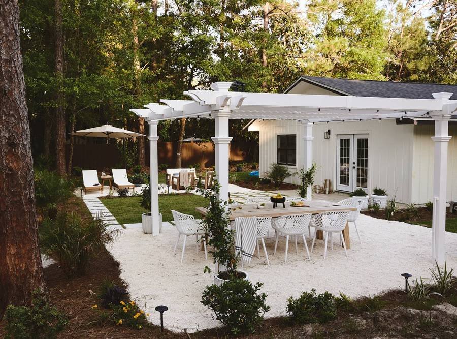 Outdoor dining are on white gravel with traditional white pergola