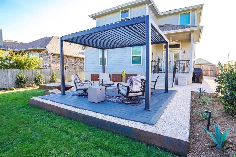 gravel patio with modern fire pit seating area covered by louvered pergola