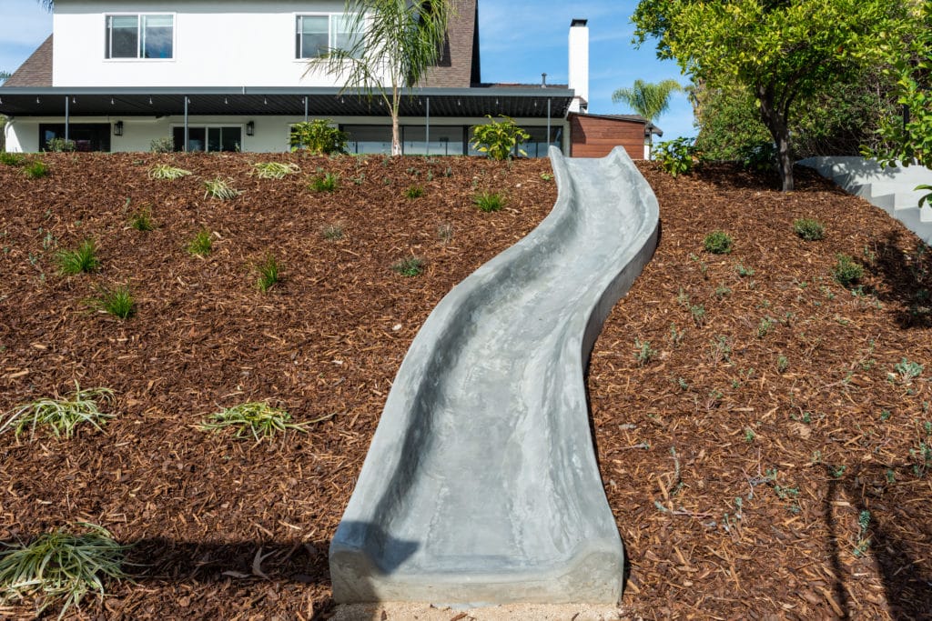 Yardzen sloped backyard landscape design featuring built-in slide