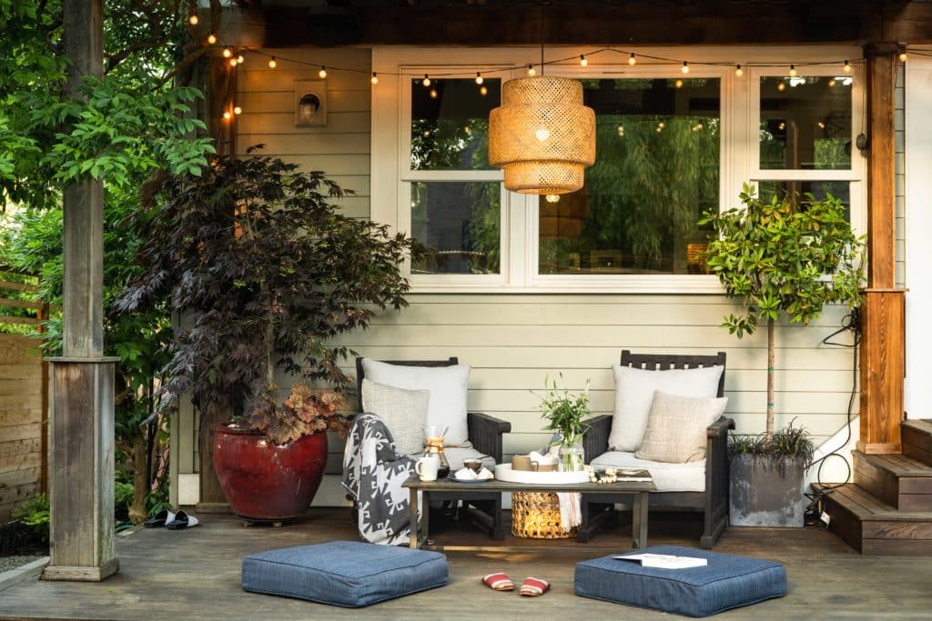 modern bohemian backyard porch with string lights, lounge furniture and hanging light