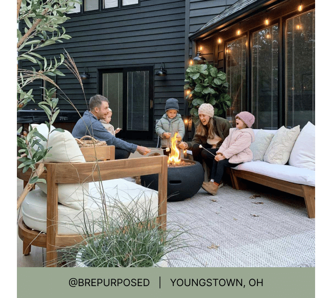 Family with three children wearing warm clothing on their back porch roasting marshmallows around a fire pit with heading that reads @brepurposed Youngstown, OH