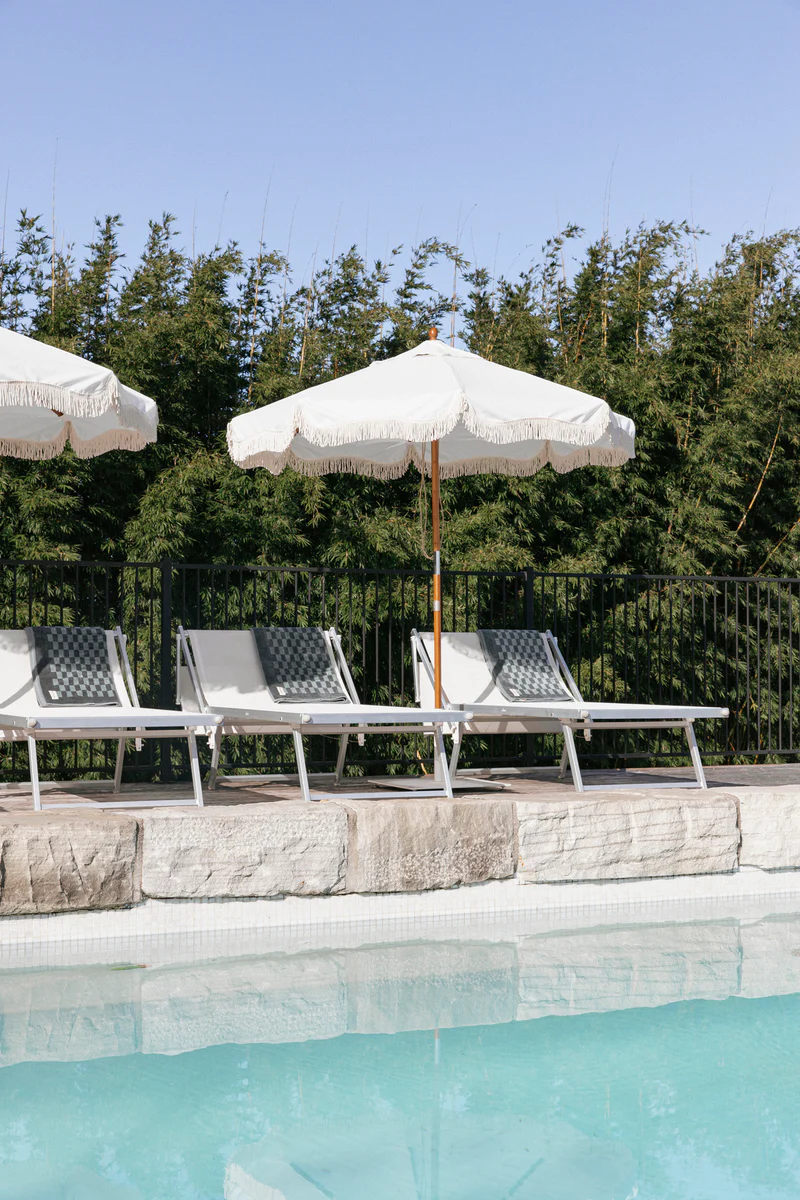 A series of Market Umbrellas shading poolside lounge chairs