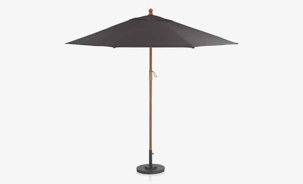 The Round Sunbrella Outdoor Patio Umbrella by Crate and Barrel in Black with a wooden pole and black stand
