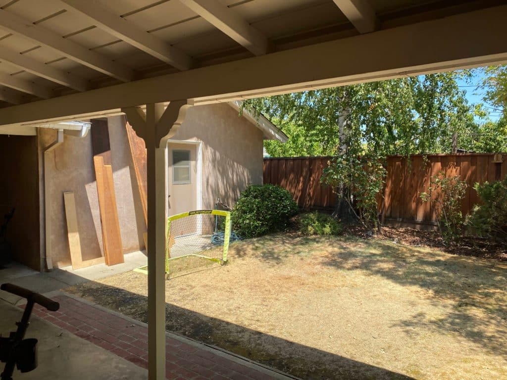 Uninspired backyard with dying grass and muddy-colored home exterior.