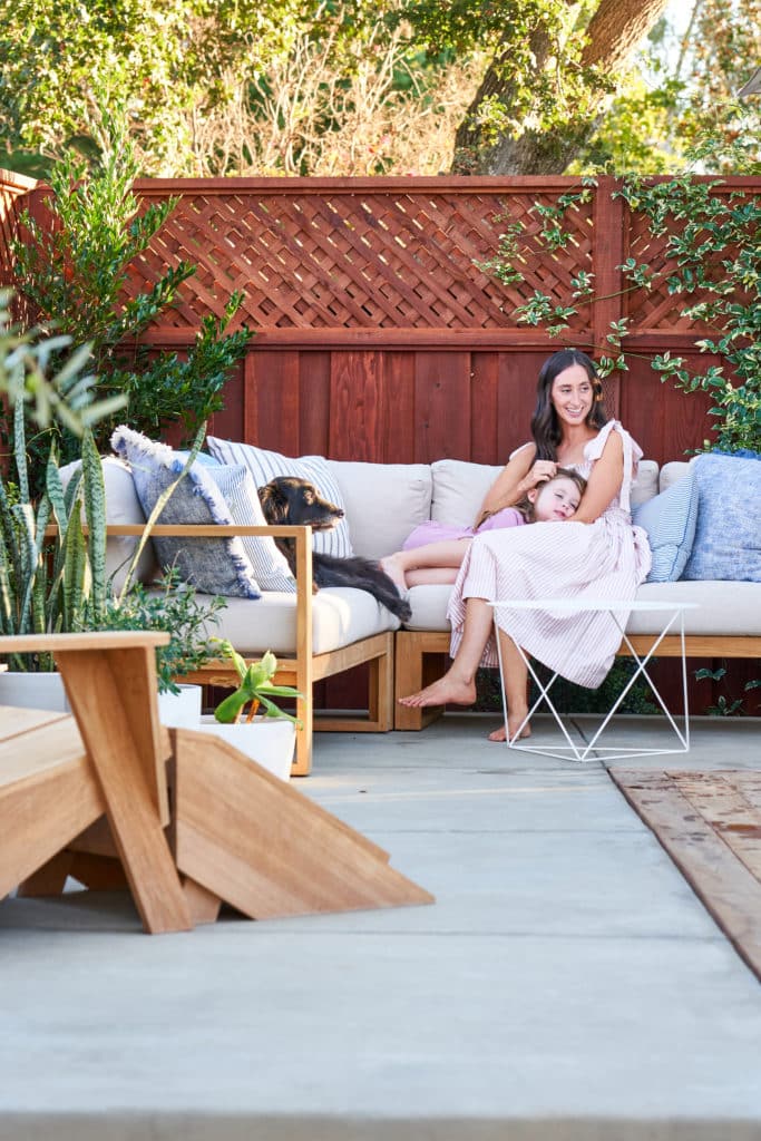 Kristy, her daughter, and the family dog enjoying their outdoor sectional on their new concrete patio.