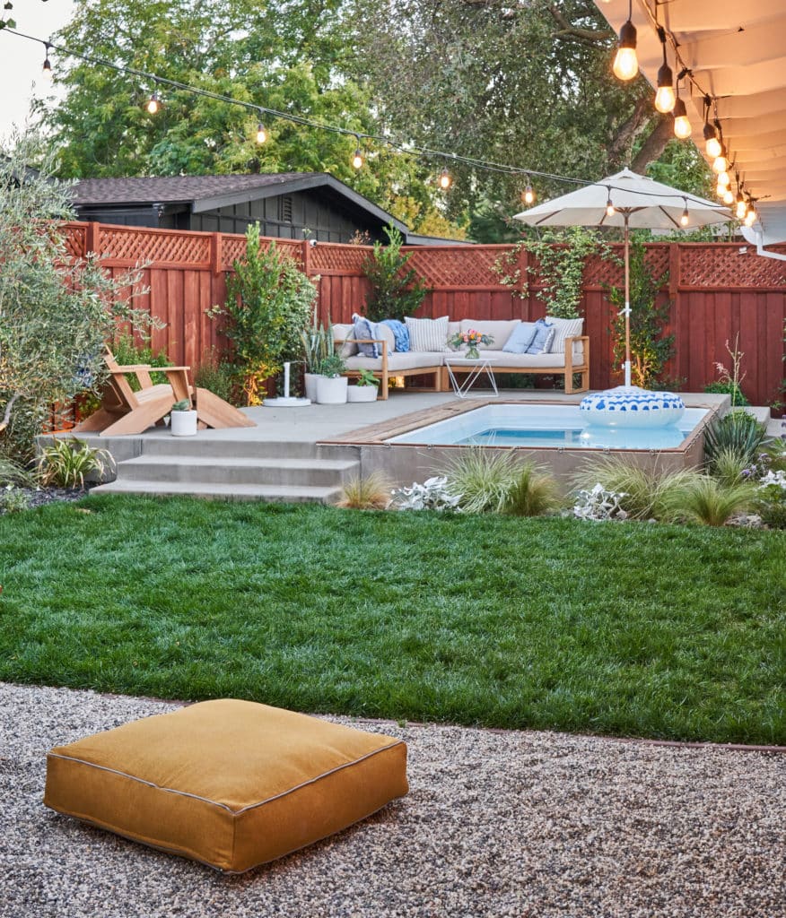 View of thriving lawn, new ornamental plantings, and heated plunge pool with concrete patio durround and seating area from outdoor fire pit seating area.