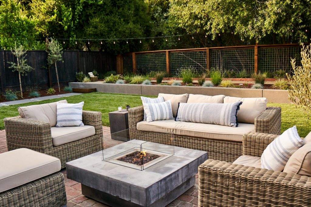 Outdoor fire pit area with comfortable outdoor couch and club chairs in a Yardzen backyard