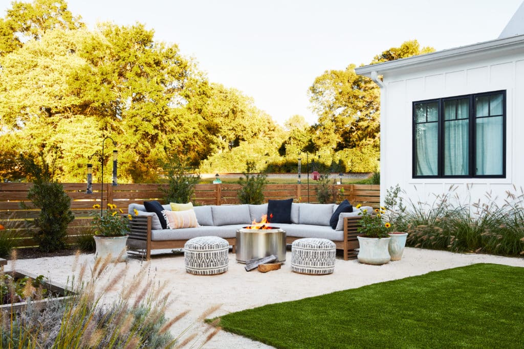 Graveled backyard, plants, a lounging couch, and a smokeless steel fire pit next to a lawn