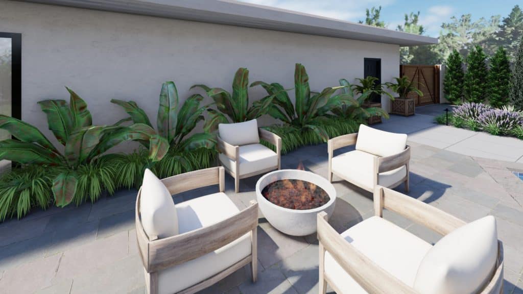 fire bowl surrounded by four outdoor lounge chairs in small backyard on paver patio with tropical plants behind