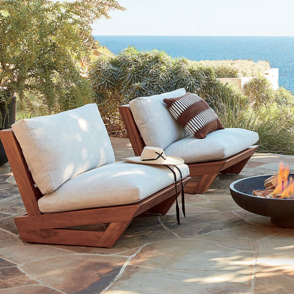 Teak outdoor chairs with white cushions near fire pit