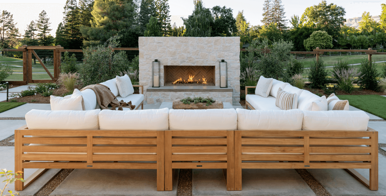 Outdoor fireplace with beautiful wooden couch with light cushions in California