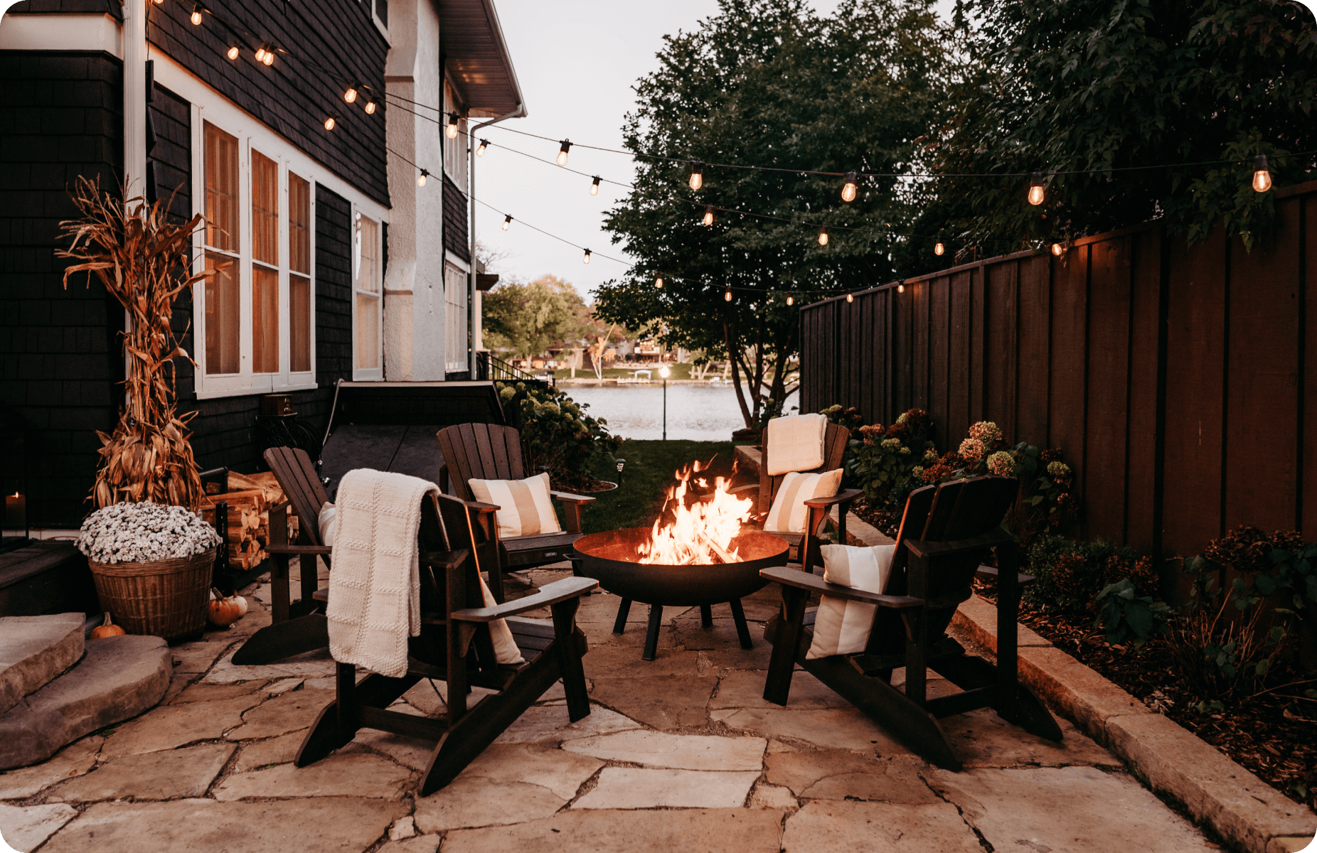 Firepit to the side of a house with a lake in the background