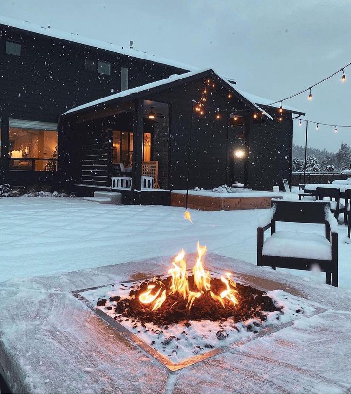 Backyard fire pit in winter with black house exterior