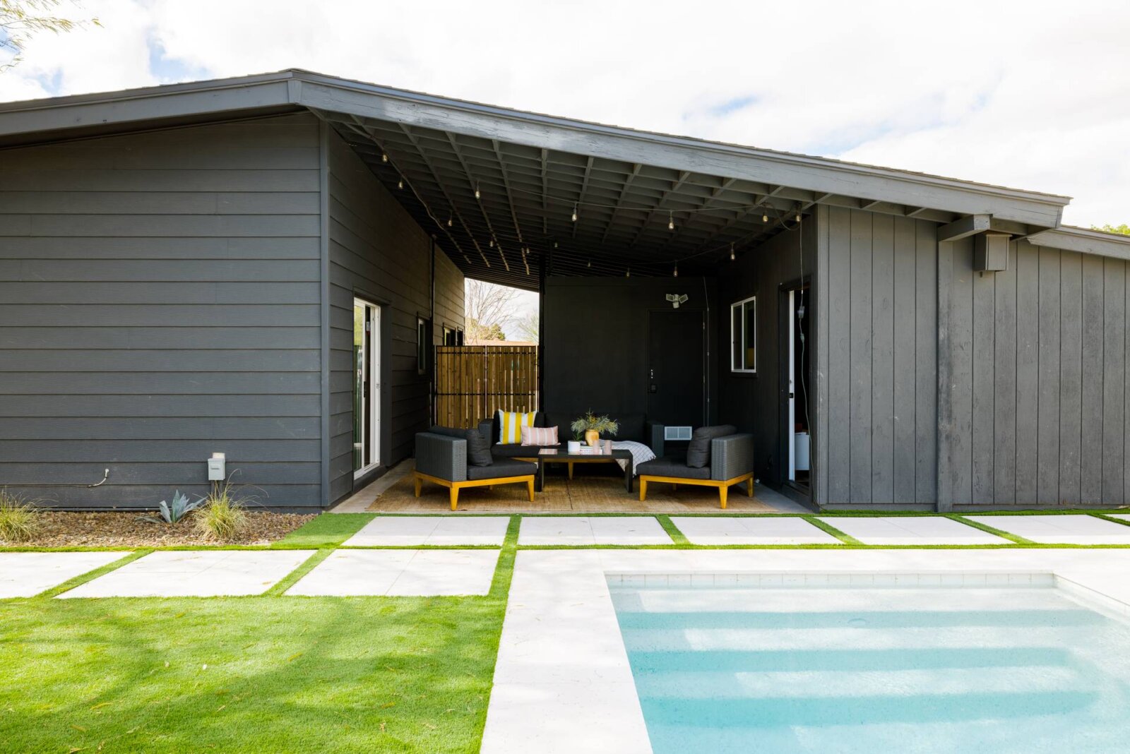 Dark charcoal house exterior near plunge pool with outdoor lounge area