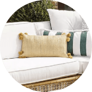 Yellow pillow with little puffs on a rattan sofa.