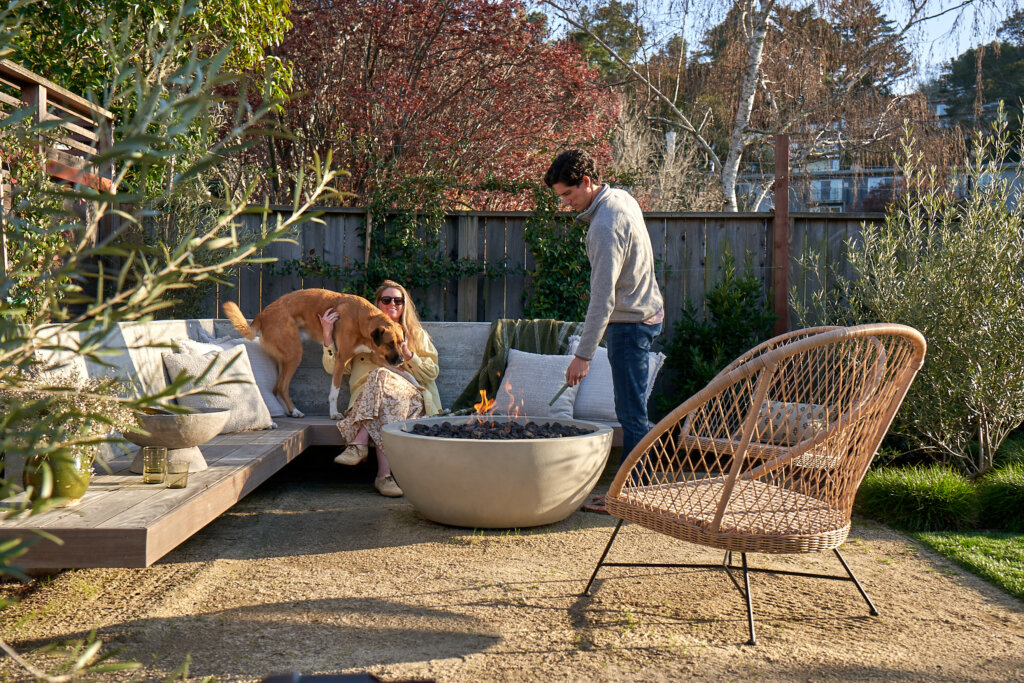 Couple with their dog around fire pit in backyard
