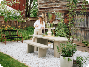 Woman standing by a concrete picnic table in her garden.