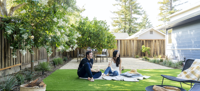 Man and Woman sit on a blanket in a grassy backyard