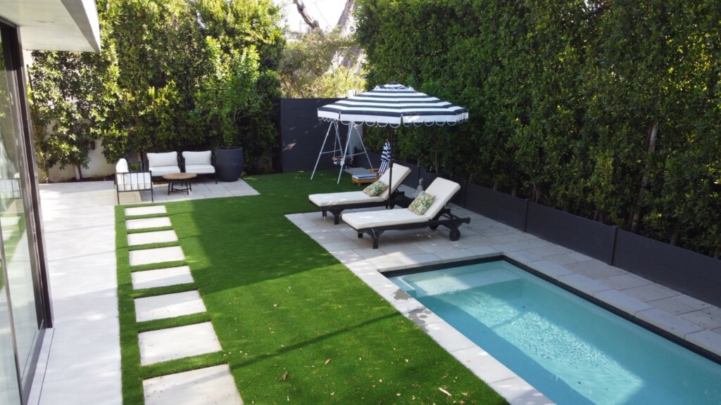 Outdoor lounge area with black and white umbrella near small plunge pool in modern backyard
