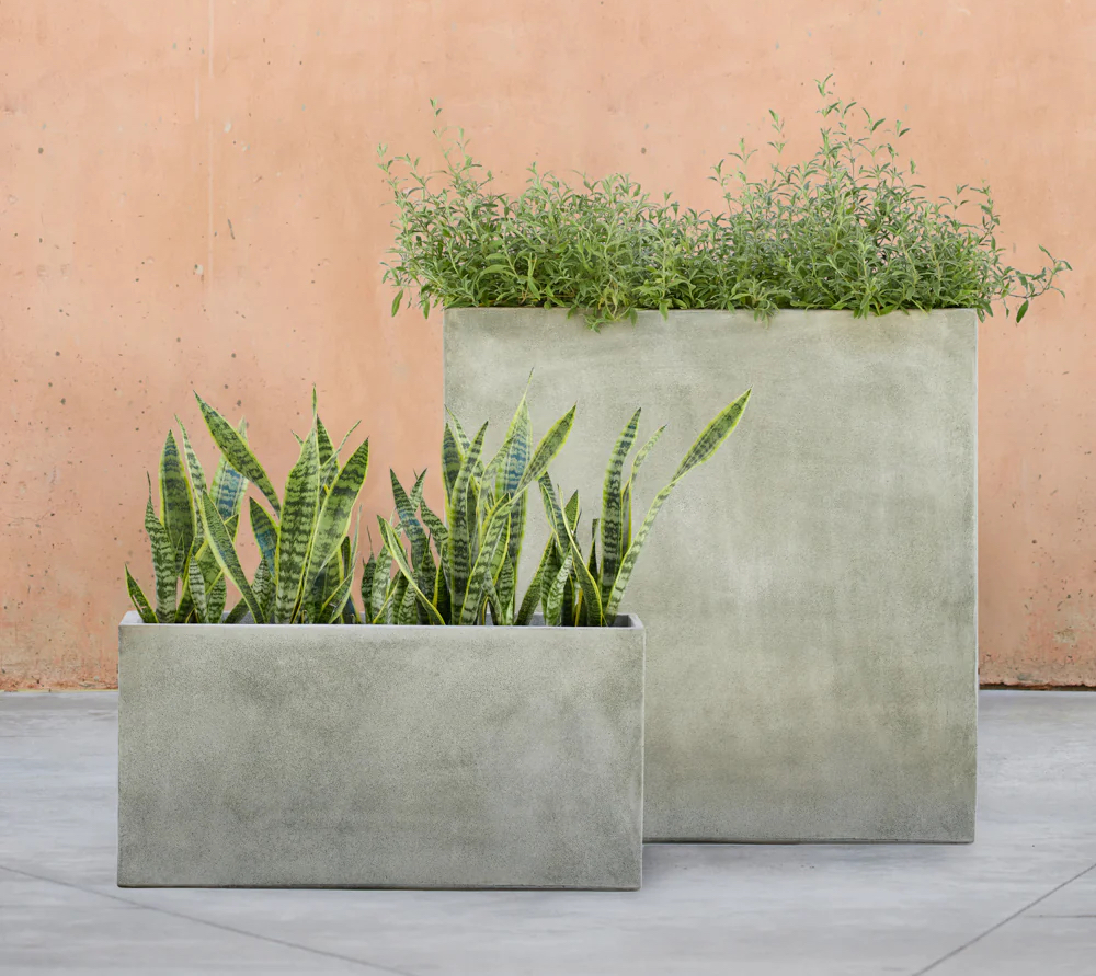 Two grey metal planter boxes with plants inside