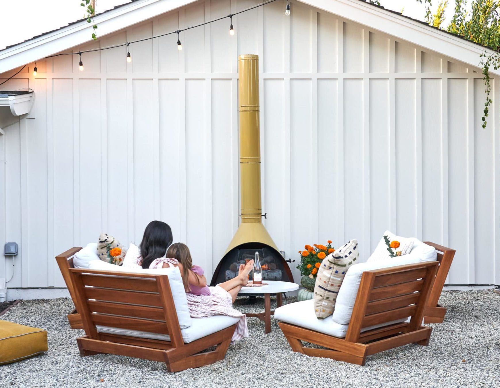 Mother and daughter sitting in outdoor lounge chairs in front of vintage chimenea