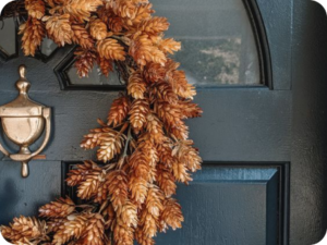 Dried orange wreath on a black front door with brass knocker.