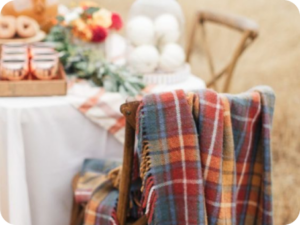 Plaid Blanket draped over a wooden chair by a table with fall decor items on it.
