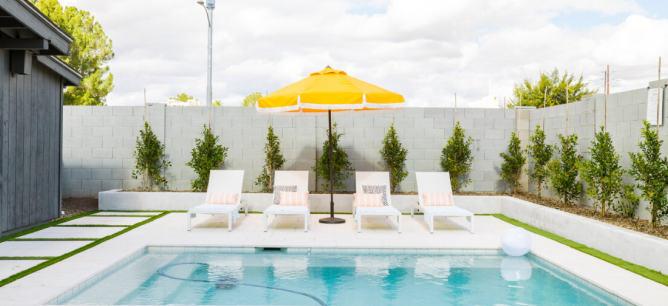 Photo of a pool with sun chairs and a yellow umbrella.