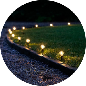 Lights on stakes in the grass along a gravel pathway.