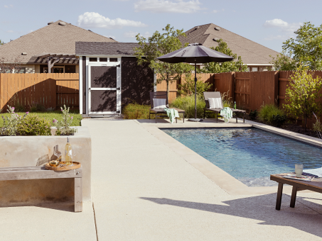 Photo of finished yard with pool, lounge furniture, shed, built-in planters, and bench