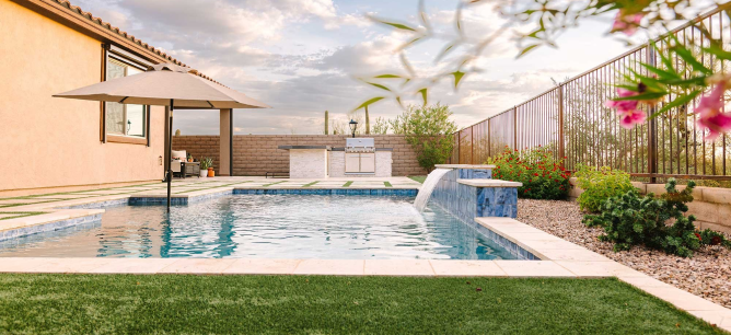 Backyard pool in Tucson with pink flowers and turf.