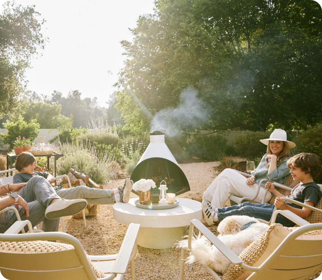 Family sitting on a gravel patio around a coffee table and chimenea