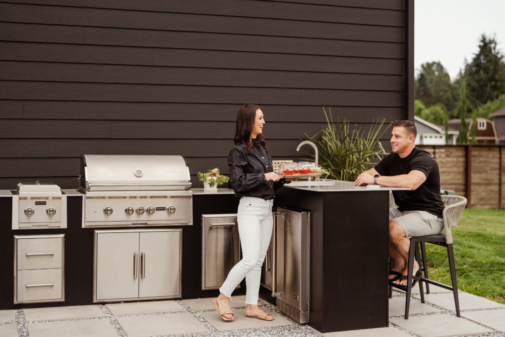 Modern outdoor kitchen in a backyard against a modern black house exterior